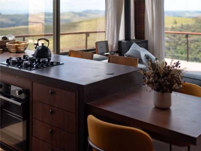 Cozinha completa com ilha de madeira, cooktop e janelas amplas sobre o vale